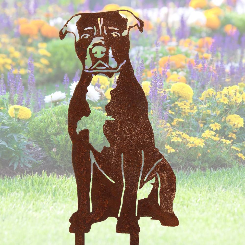 Corten steel garden art stakes and a dog statue among plants